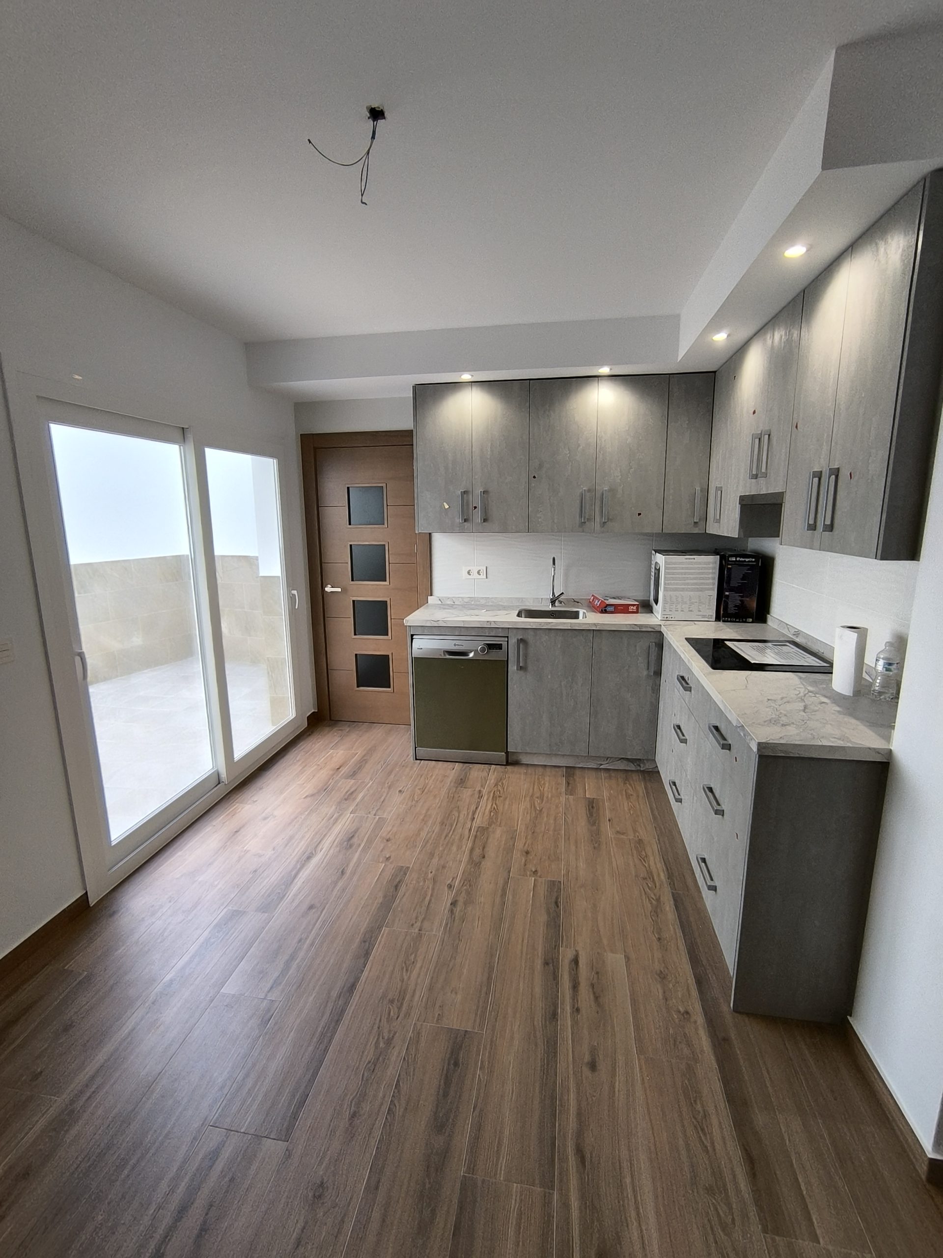 Cocina moderna con acabados en madera y mobiliario gris construida por empresa de construcción en Antequera